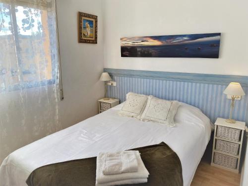 Schlafzimmer mit einem Bett mit weißer Bettwäsche und Kissen in der Unterkunft Beachfront and Peaceful Apartment in Mareny Barraquetas