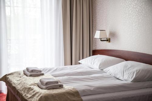 a bedroom with a bed with two towels on it at Hotel Stara Gorzelnia in Licheń Stary