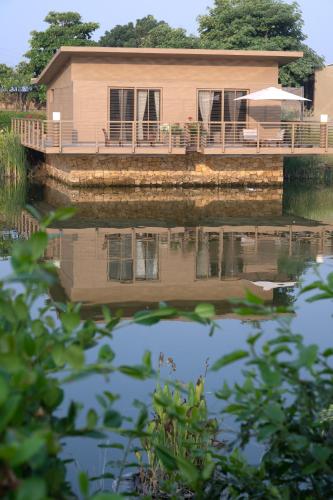 a house is reflected in a body of water at Life At REPOSE- Lake Villas Resort & Club in Chor Warodra