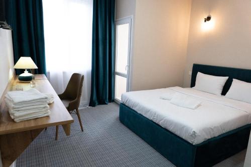 a hotel room with a bed and a table and a desk at Jardin in Aktobe