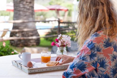 a woman sitting at a table with a tray of food at Country Hotel Residence Da Pilade in Capoliveri