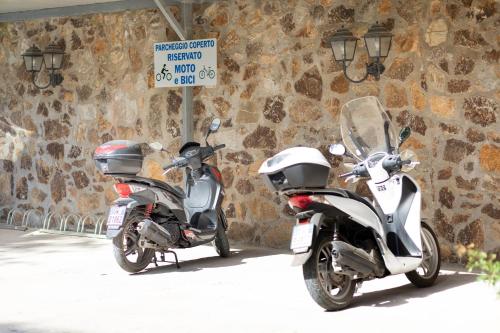 two motor scooters parked next to a stone wall at Country Hotel Residence Da Pilade in Capoliveri