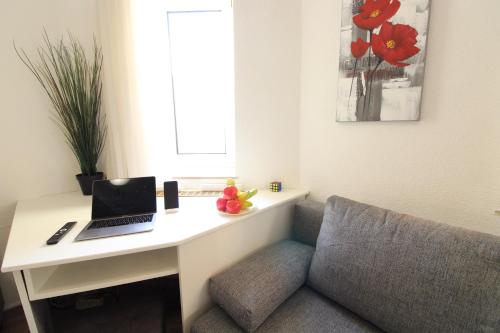 a room with a desk with a laptop and a couch at Downtown Apartments Ulm - im Herzen von Ulm & komfortable Boxspringbetten in Ulm