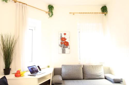 a living room with a couch and a desk with a laptop at Downtown Apartments Ulm - im Herzen von Ulm & komfortable Boxspringbetten in Ulm