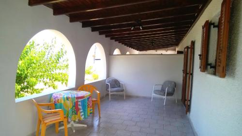 a patio with chairs and a table and two windows at IONIO Apartments in Lefkímmi