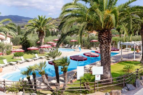 a resort with a pool with palm trees and umbrellas at Country Hotel Residence Da Pilade in Capoliveri