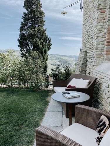a patio with two chairs and a table and a tree at Relais San Maurizio in Santo Stefano Belbo