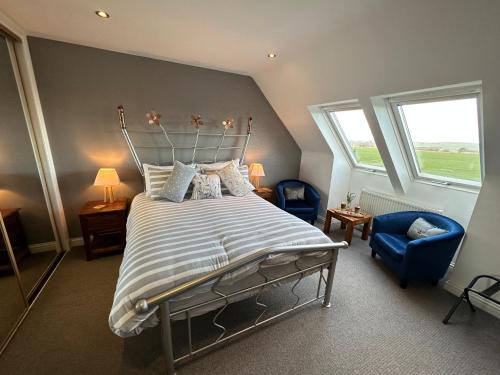 Tarskavaig Bed & Breakfast في Radernie: غرفة نوم بسرير وكرسي ازرق