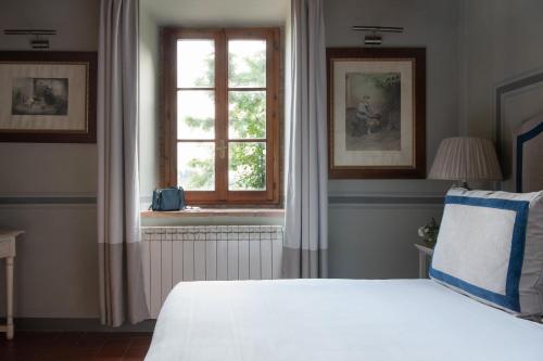 a bedroom with a white bed and a window at Relais Villa Olmo - Place of Charme in Impruneta