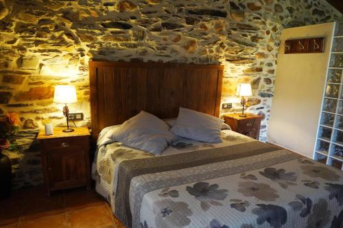 1 dormitorio con cama y pared de piedra en Los Monteros Sierra de Francia, en Aldeanueva de la Sierra