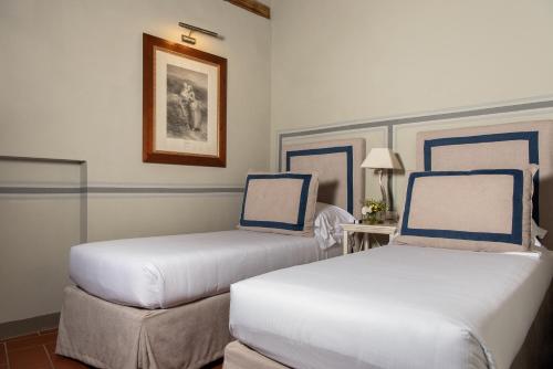 a room with two beds with blue and white pillows at Relais Villa Olmo - Place of Charme in Impruneta