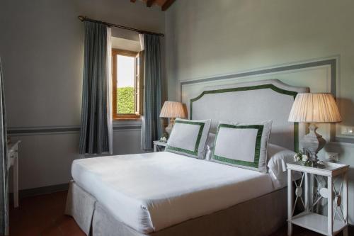 a bedroom with a large white bed with green pillows at Relais Villa Olmo - Place of Charme in Impruneta