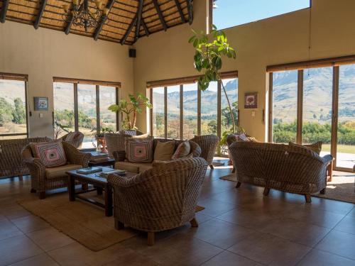 a living room with chairs and tables and windows at Silver Hill Lodge in Kamberg Valley