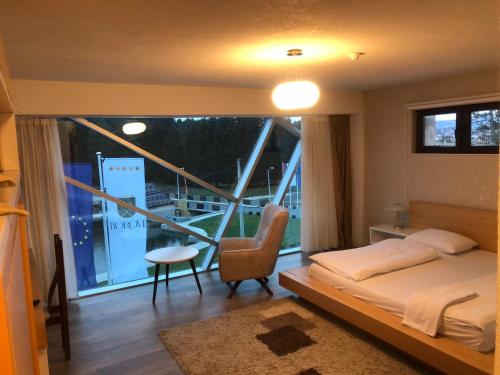 a bedroom with a bed and a large window at Hotel Borovi Forest Resort & Spa in Sjenica
