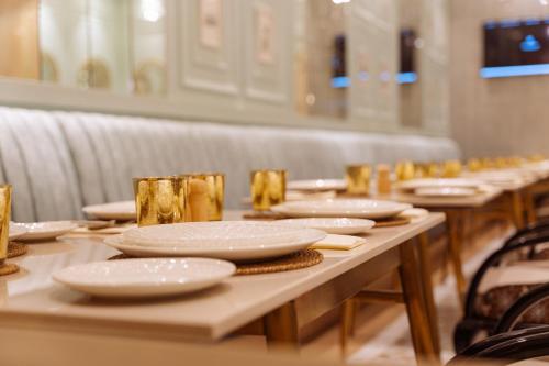 a long wooden table with white plates on it at The Greenwood Guwahati - A Luxury Boutique Hotel in Guwahati