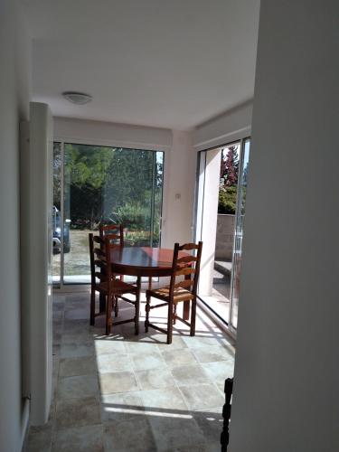 a dining room with a table and chairs and windows at Le Rocher au Thym in Limoux