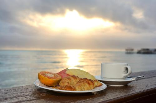 een bord eten en een kopje koffie op een tafel bij Mnarani Beach Cottages in Nungwi