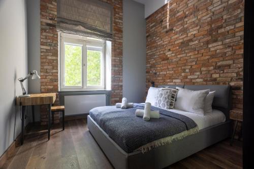 a bedroom with a brick wall and a bed and a desk at Tyzenhauz Apartments Superior in Krakow