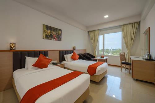 a hotel room with two beds and a desk at Sterling V Grand Madurai in Madurai