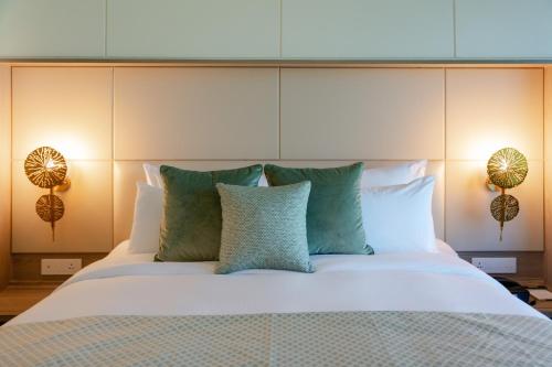 a large bed with white sheets and green pillows at The Greenwood Guwahati - A Luxury Boutique Hotel in Guwahati