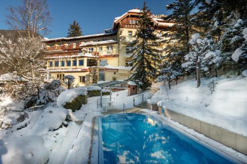a swimming pool covered in snow in front of a building at Hotel Alpenblick in Bad Gastein