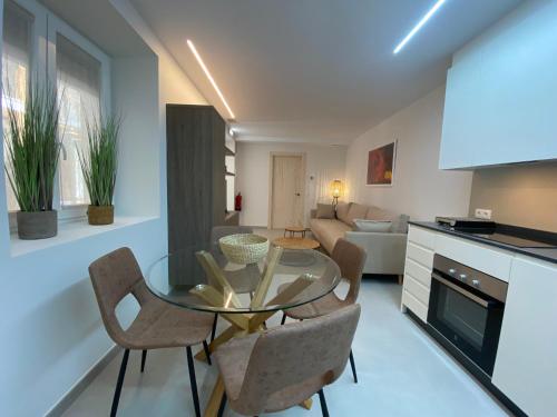a kitchen and living room with a glass table and chairs at IBSEN Almagro in Almagro