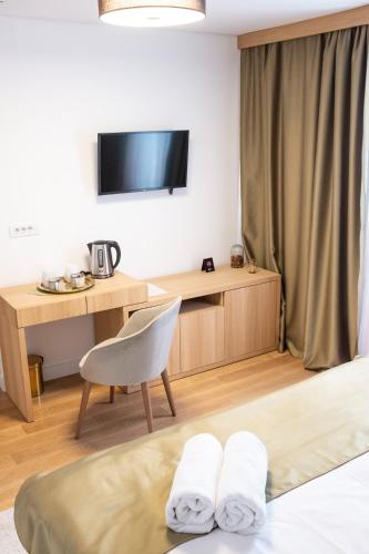 a hotel room with a bed and a desk and a tv at Prenoćište restoran Bukulja in Arandjelovac