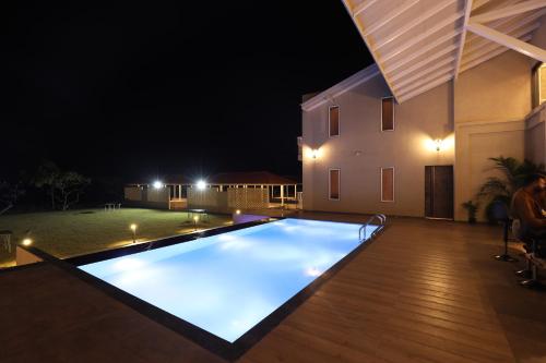 a swimming pool at night with a house at Isola Luxury Farm Suites in Nashik