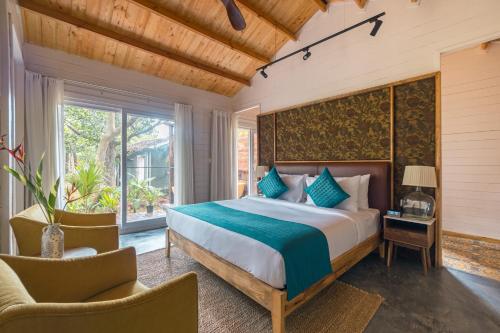 a bedroom with a large bed and two chairs at Larisa Resort Ashwem in Mandrem