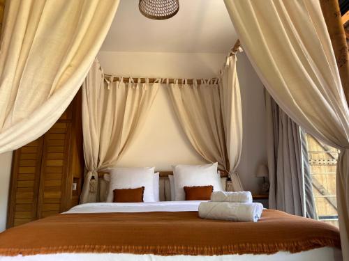 una camera da letto con un grande letto con tende di LES VAVANGUES - L'HERMITAGE LES BAINS a La Saline Le Bains