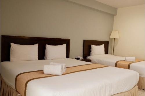 a hotel room with two beds with white sheets at Phromsuk Hotel Ayutthaya in Phra Nakhon Si Ayutthaya