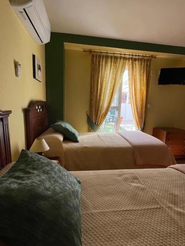 a hotel room with two beds and a window at Hotel Arunda II in Ronda