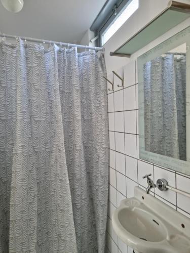 y baño con cortina de ducha y lavamanos. en De Juttershut, en Egmond aan Zee