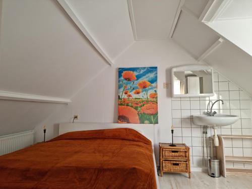 1 dormitorio con 1 cama grande y lavamanos en De Juttershut, en Egmond aan Zee