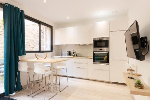 une cuisine avec des armoires blanches et une table avec des tabourets dans l'établissement La Terrasse de Charles - Appt au calme avec terrasse, à Nancy