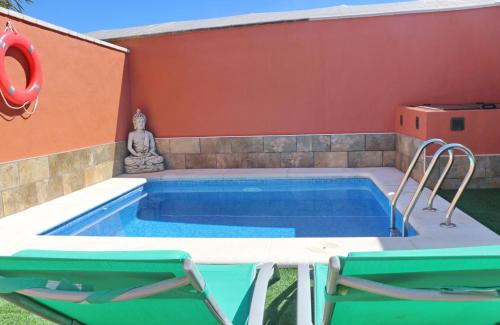 a swimming pool with two chairs next to a house at Chalet Sultan con piscina in Conil de la Frontera