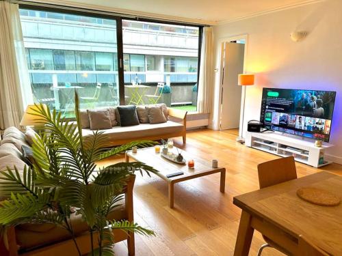 un salon avec un canapé et une télévision dans l'établissement Champs Élysées-Belle terrasse, luxueux appartement, à Paris