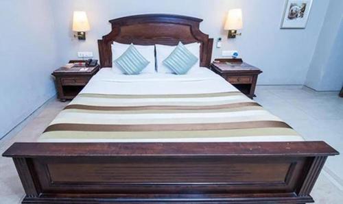 a bedroom with a large wooden bed with two tables at FabHotel Prime Neelam The Glitz in Calangute