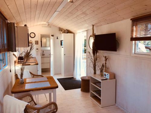 una piccola cucina con tavolo e sedie in una casetta di Zirkuswagen mit Outdoor Whirlpool und Garten a Petershagen