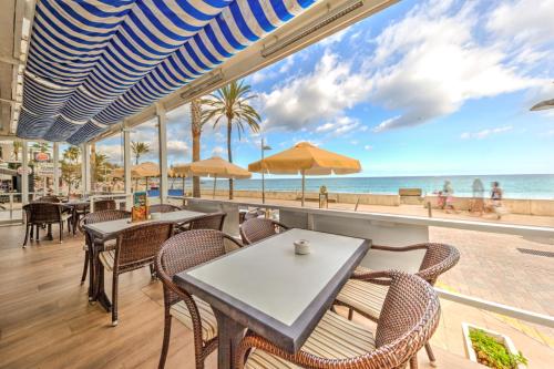 ein Restaurant mit Tischen und Stühlen und Blick auf den Strand in der Unterkunft Hotel Voramar in Cala Millor