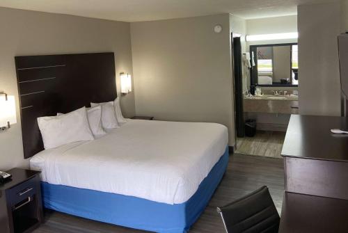 a hotel room with a large bed and a bathroom at Days Inn by Wyndham Moss Point Pascagoula in Moss Point