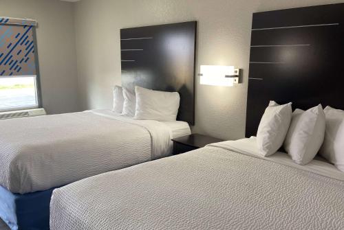 a hotel room with two beds with white pillows at Days Inn by Wyndham Moss Point Pascagoula in Moss Point