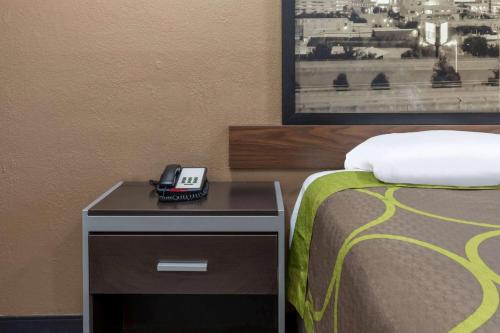 a bedroom with a bed and a phone on a night stand at Super 8 by Wyndham Tulsa/Arpt/St Fairgrounds in Tulsa
