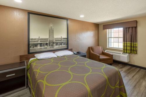 a hotel room with a bed and a chair at Super 8 by Wyndham Tulsa/Arpt/St Fairgrounds in Tulsa