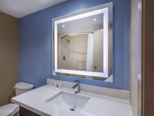een blauwe badkamer met een wastafel en een spiegel bij Super 8 by Wyndham Toronto East ON in Toronto