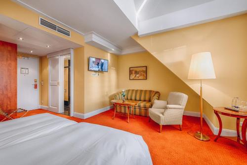a bedroom with a bed and a couch and a table at Hotel Moosburger Hof in Pfaffenhofen an der Ilm