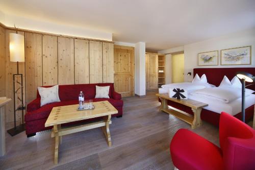 a hotel room with a red couch and a bed at Hotel Petersboden in Lech am Arlberg