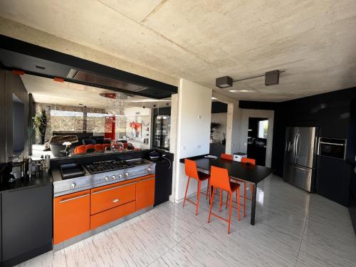 eine Küche mit orangefarbenen und schwarzen Schränken und einem Tisch in der Unterkunft Suite 28 in Treilles