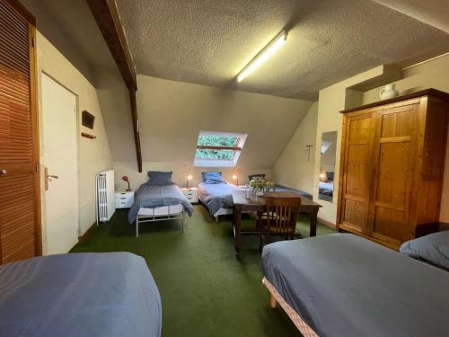 a room with three beds and a table and chairs at St Rom, Vue imprenable sur l'Ile de Bréhat in Bréhat