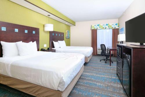 a hotel room with two beds and a flat screen tv at La Quinta by Wyndham Dallas Grand Prairie South in Grand Prairie